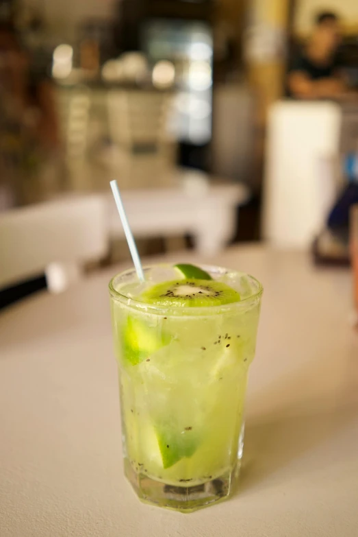 a close up of a drink in a glass on a table, lime green, 3/4 side view, battered, multiple stories