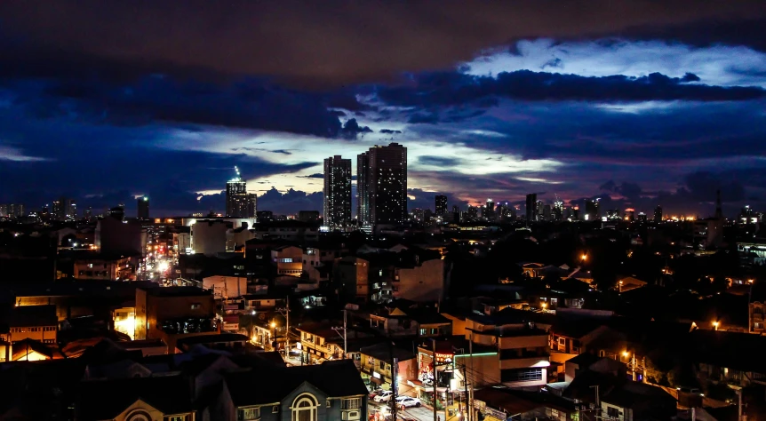 an aerial view of a city at night, by Basuki Abdullah, pexels contest winner, with dramatic sky, manila, from the roof, summer evening