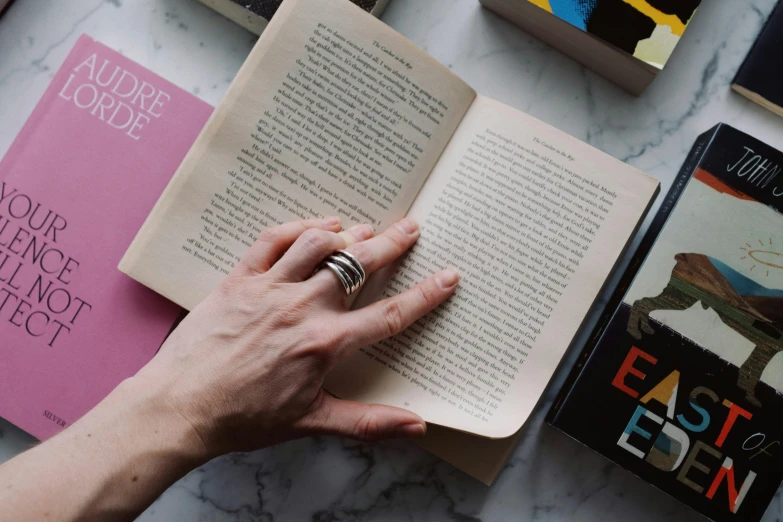 a person reading a book on a marble table, pexels contest winner, private press, hook as ring, holding books, the ring, bookshelf