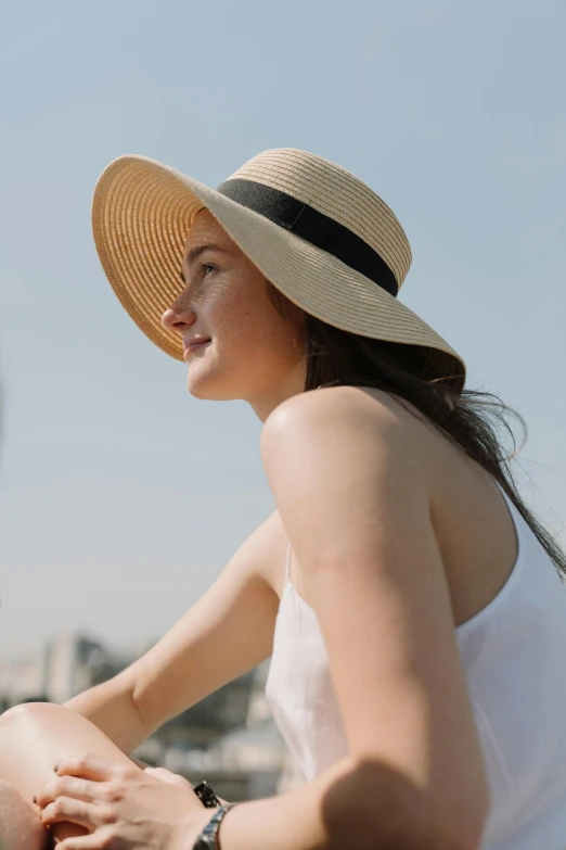 a woman sitting in front of the eiffel tower, white straw flat brimmed hat, neck zoomed in, sunfaded, engineered