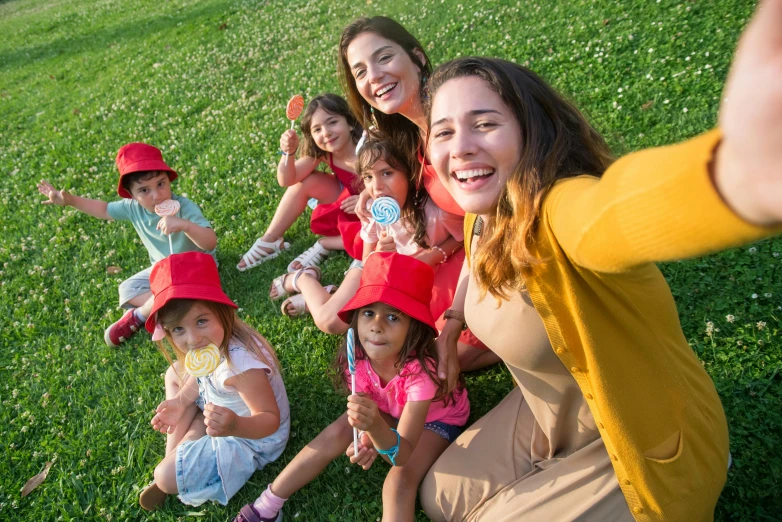 a group of children sitting on top of a lush green field, 8k selfie photograph, of a family standing in a park, holding maracas, avatar image