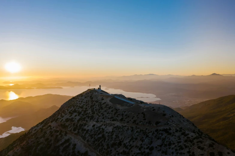 a person standing on top of a mountain at sunset, by Niko Henrichon, unsplash contest winner, les nabis, greece, “ aerial view of a mountain, bay area, tucson arizona