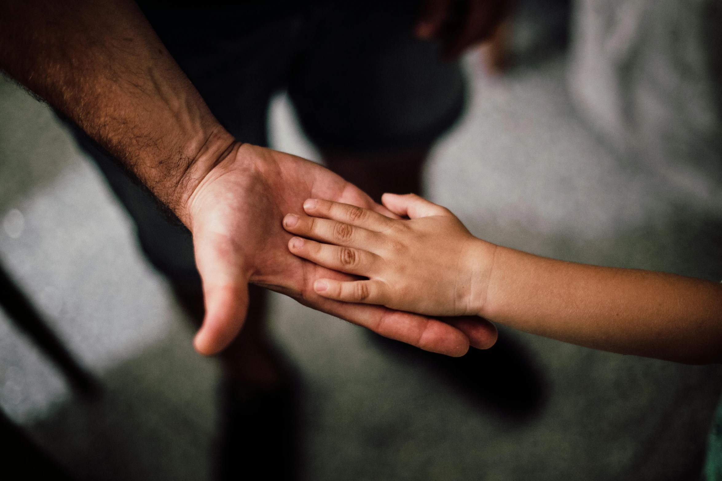 a close up of a person holding a child's hand, photo of a man, uploaded, brown, low light