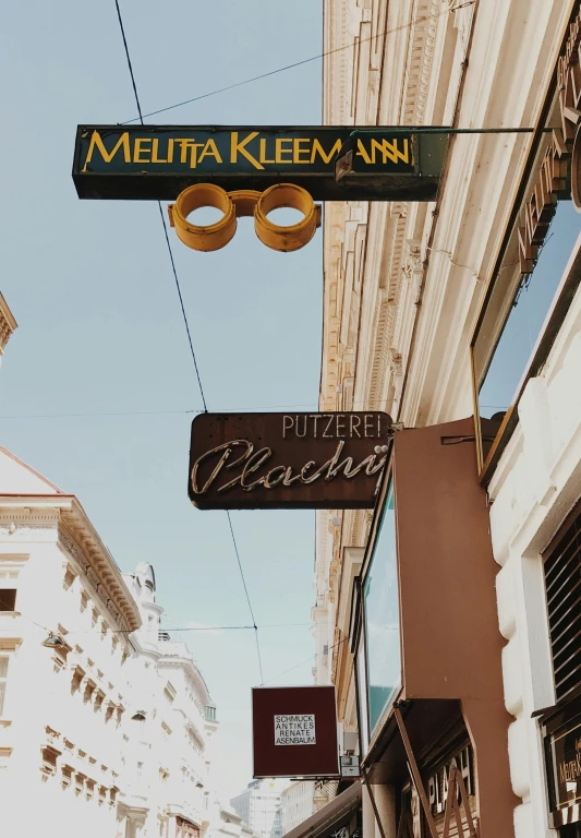 a couple of signs hanging from the side of a building, by Micha Klein, trending on unsplash, viennese actionism, pizza is everywhere, 💋 💄 👠 👗, colonial era street, alana fletcher
