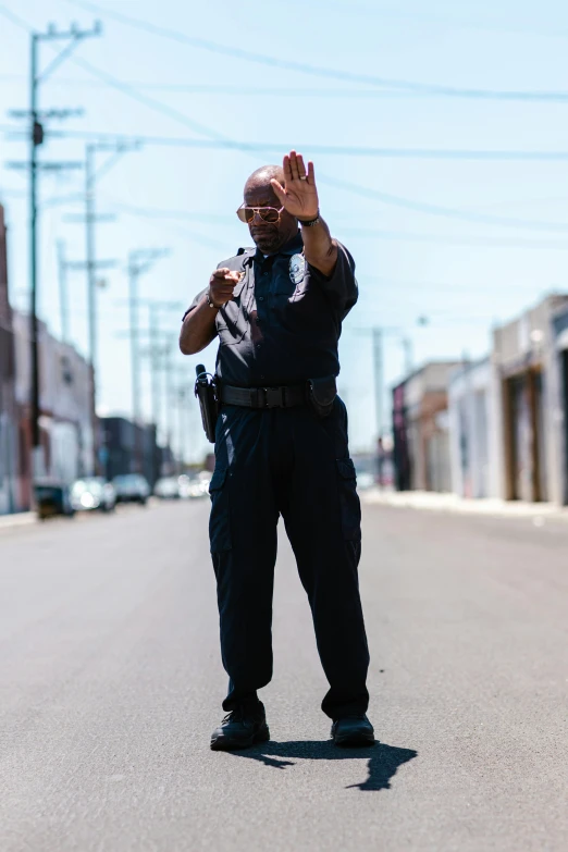 a police officer standing in the middle of a street, by Carey Morris, happening, raised hand, documentary, essence, security rhox