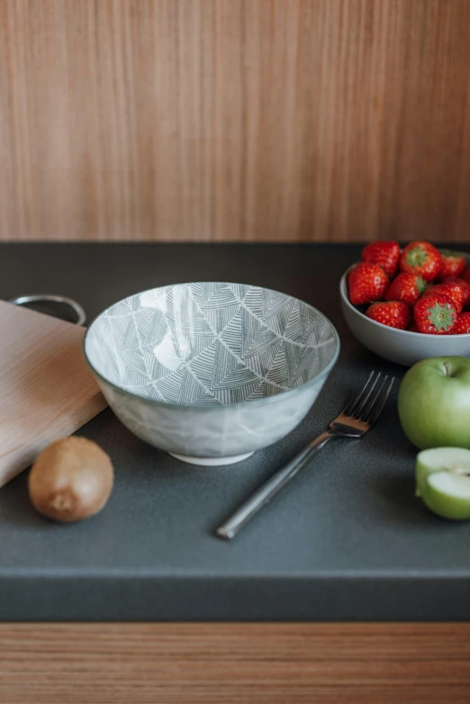 a cutting board sitting on top of a counter next to a bowl of fruit, inspired by Constantin Hansen, botanic foliage, celadon glaze, grey, fruit bowl