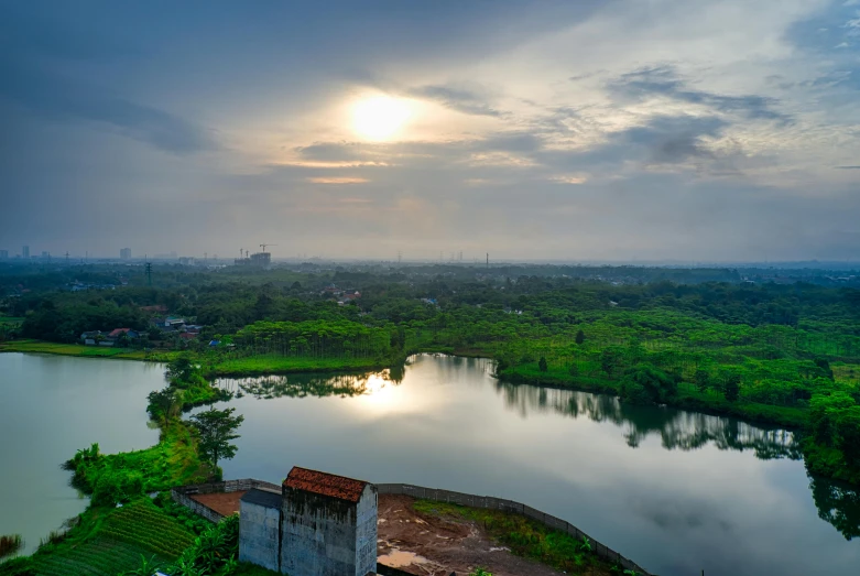 a large body of water sitting next to a lush green forest, a matte painting, pexels contest winner, hurufiyya, indore, vista of a city at sunset, industrial surrounding, a photo of a lake on a sunny day