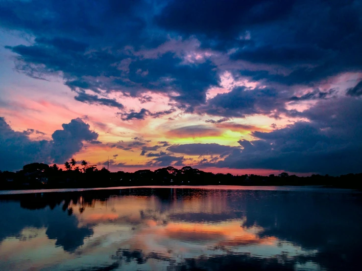 a large body of water under a cloudy sky, by Reuben Tam, pexels contest winner, hurufiyya, colorful sunset, parks and lakes, fan favorite, blue and pink colors