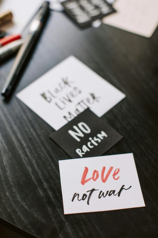 a couple of stickers sitting on top of a table, a black and white photo, pexels, protest, colored marker, love theme, any racial background