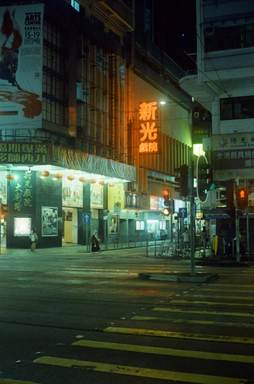 a city street at night with people crossing the street, by Patrick Ching, graffiti, 1980s photograph, hong kong, yellow, old cinema