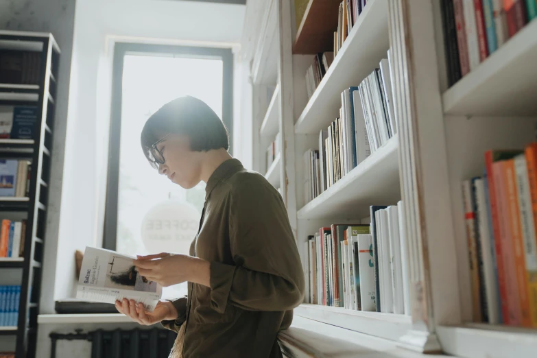 a woman reading a book in a library, pexels contest winner, standing in corner of room, androgynous person, profile image, japanese