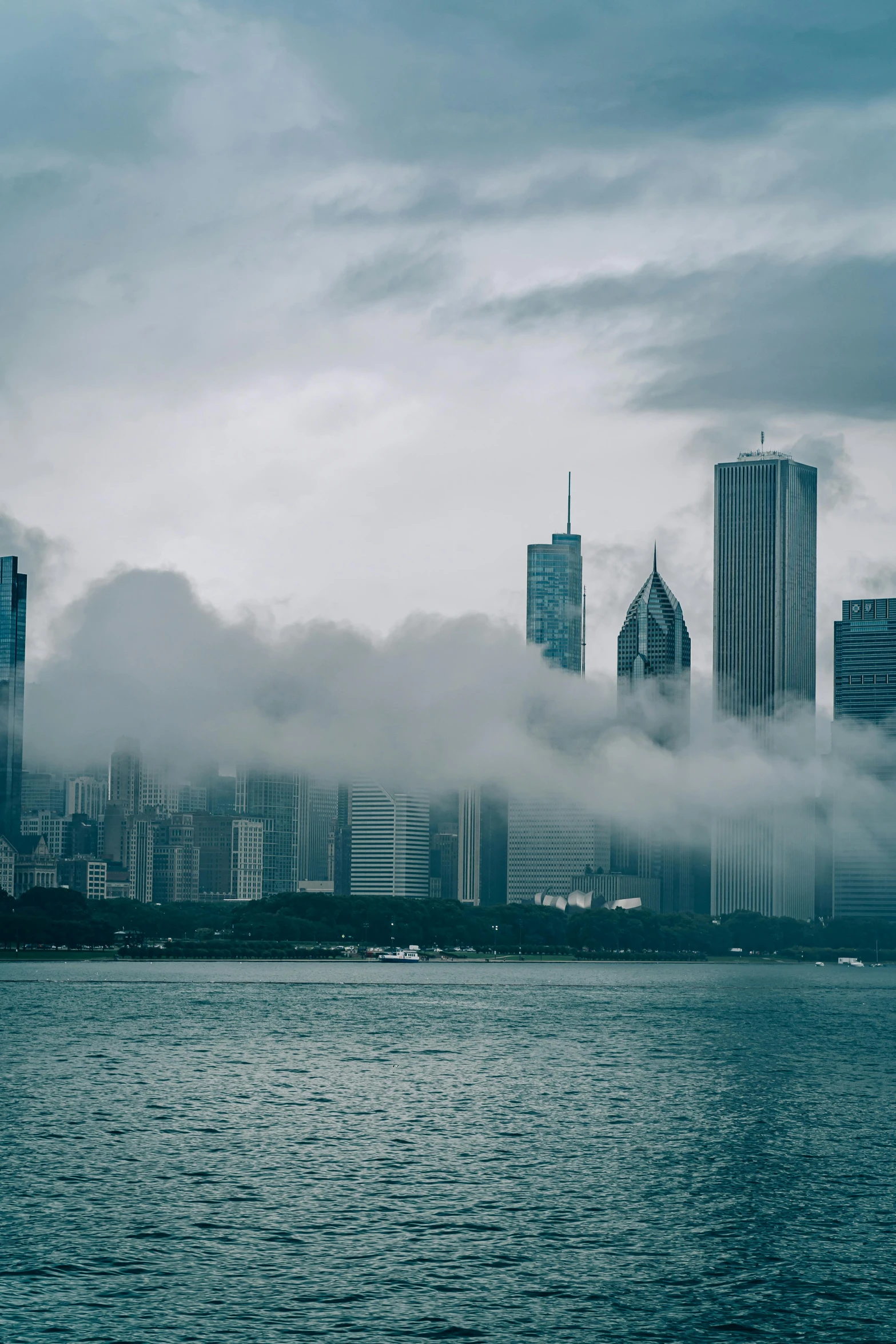 a large body of water with a city in the background, by Greg Rutkowski, pexels contest winner, covered in clouds, chicago, spooky photo, multiple stories