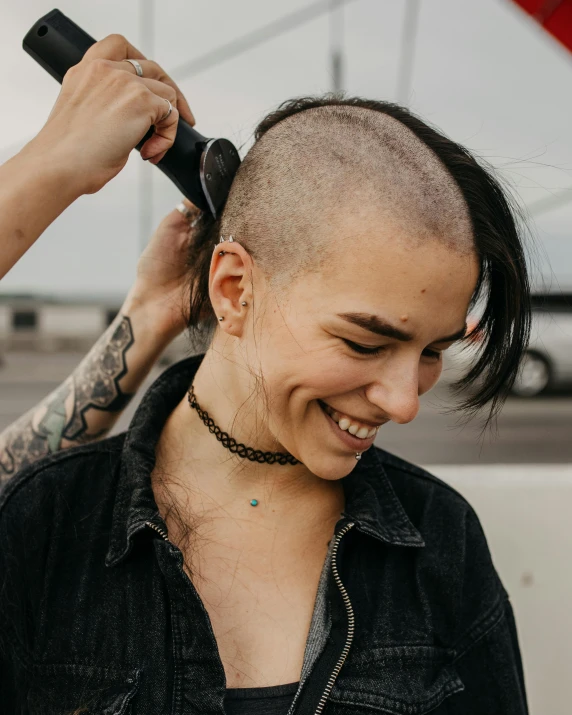 a woman with a shaved head cutting another woman's hair, trending on pexels, antipodeans, a still of a happy, non-binary, pictured from the shoulders up, kailee mandel