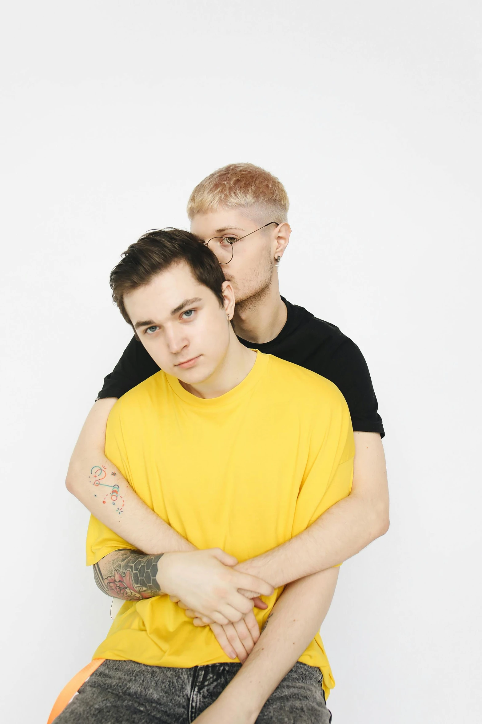 a couple of men sitting next to each other, an album cover, pexels, antipodeans, yellow hair, lesbian, crossed arms, standing straight