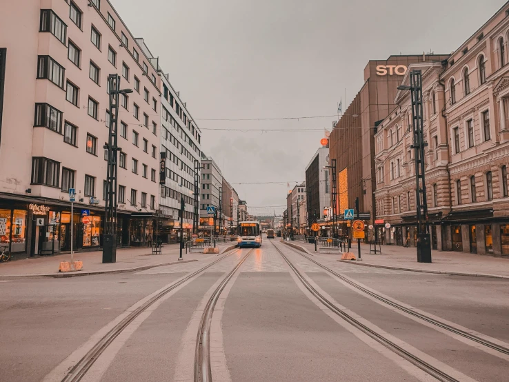 a car driving down a street next to tall buildings, by Christen Dalsgaard, pexels contest winner, helsinki, orange line, calm evening, square