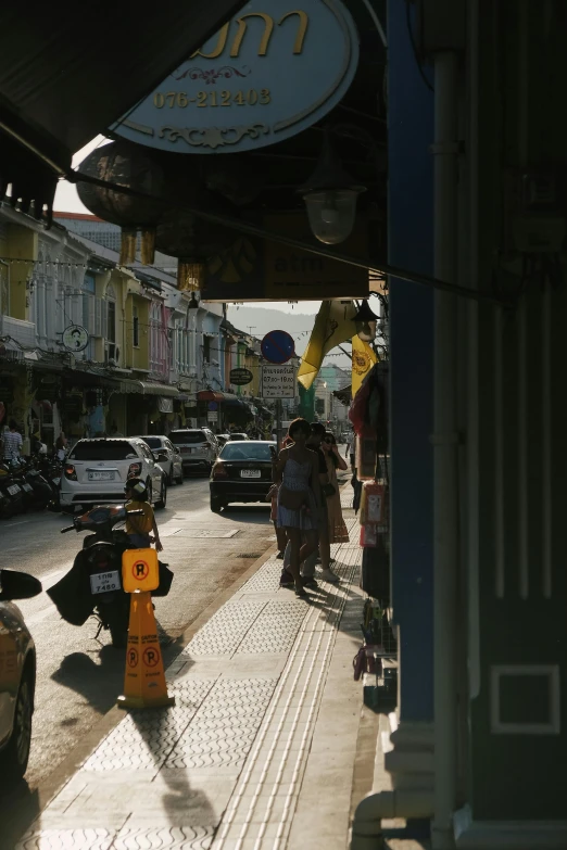 a street filled with lots of traffic next to tall buildings, by Max Buri, old shops, thai architecture, sunlight shining through, a small