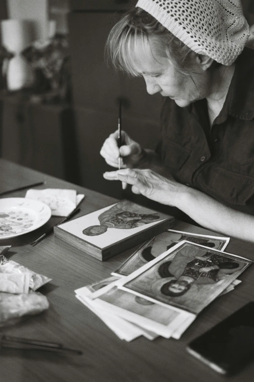 a black and white photo of a woman sitting at a table, a detailed painting, process art, sketching, plating, holy iconography, taken in the late 2000s