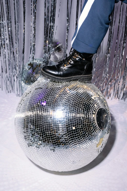 a person standing on top of a disco ball, wearing boots, posing for a picture, up close, february)