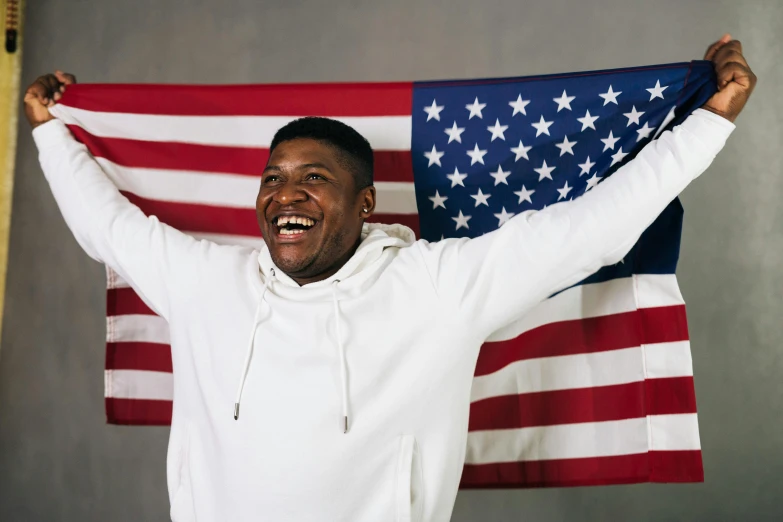 a man holding an american flag over his head, pexels contest winner, brown skin man with a giant grin, ray lewis, yung lean, celebrating an illegal marriage