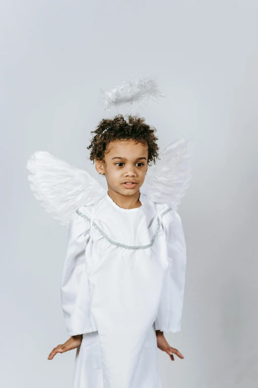 a little girl dressed up as an angel, an album cover, pexels contest winner, renaissance, plain background, young boy, diverse costumes, high resolution product photo