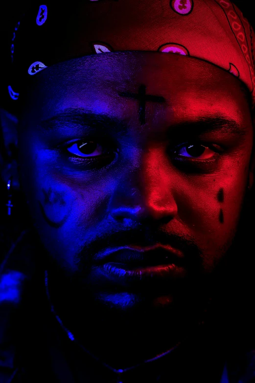 a man with blue and red paint on his face, an album cover, by Bascove, renaissance, neon cross, kendrick lamar, with red glowing eyes, ( ( theatrical ) )