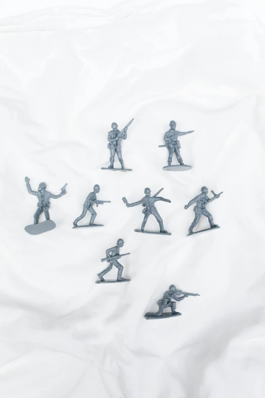 a group of toy soldiers sitting on top of a white sheet, in gunmetal grey, product shot, plastic, display item