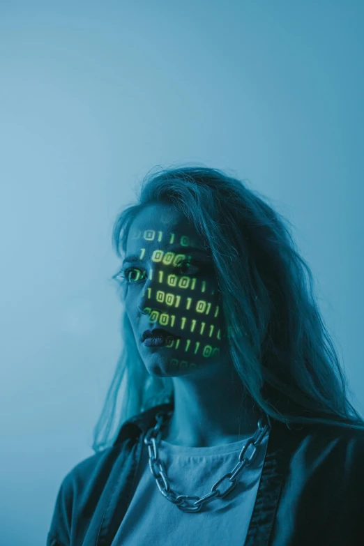 a woman standing in front of a computer screen, a hologram, by Adam Marczyński, trending on pexels, ascii art, markings on her face, binary, discord profile picture, cybernetic dreadlocks