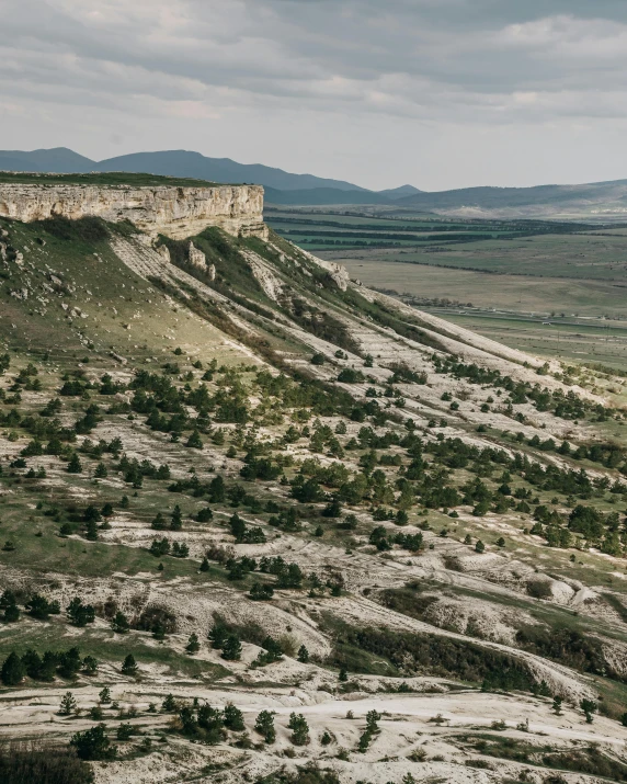 a man riding a motorcycle down a dirt road, by Emma Andijewska, unsplash contest winner, art nouveau, geological strata, overlooking a valley with trees, southern slav features, an expansive grassy plain