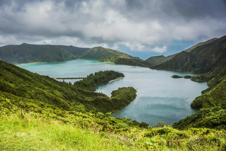 a large body of water sitting on top of a lush green hillside, by Daniel Lieske, pexels contest winner, hurufiyya, volcanic landscape, square, brocade, lagoon