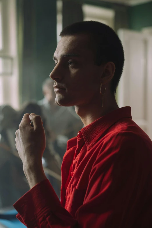 a man in a red shirt standing in front of a pool table, an album cover, inspired by Nan Goldin, trending on pexels, antipodeans, frank dillane as puck, masculine jawline, in front of a large crowd, non binary model