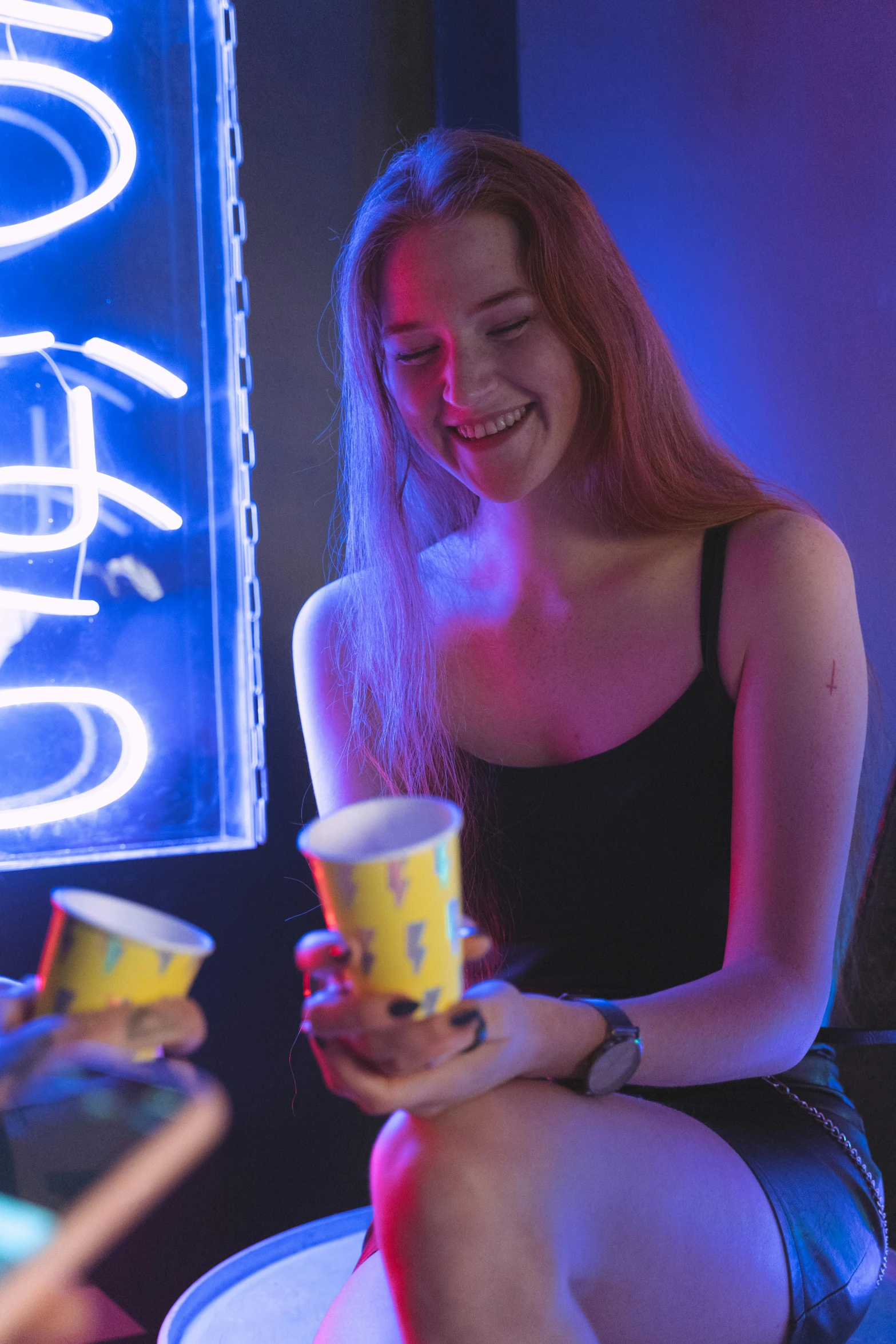 a woman sitting on a stool in front of a neon sign, by Adam Marczyński, trending on reddit, cups and balls, college party, smiling playfully, avatar image
