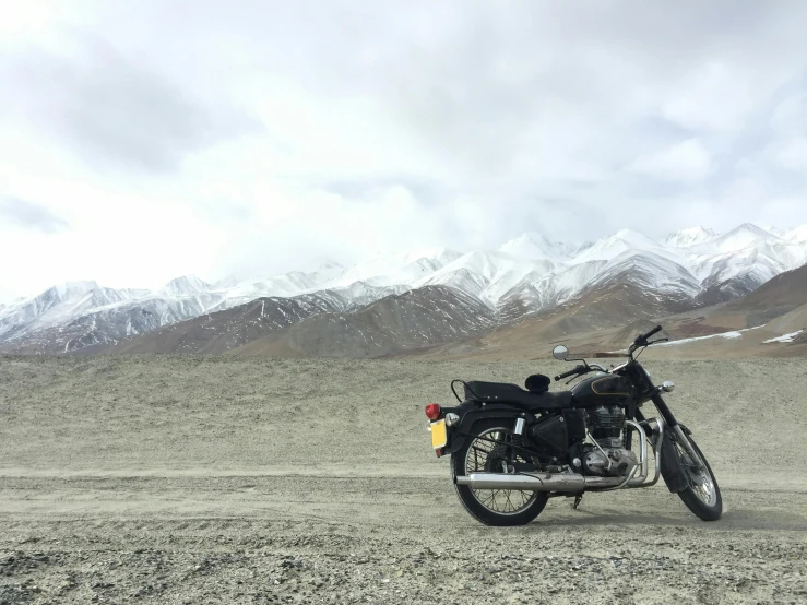 a motorcycle parked on the side of a dirt road, by Carey Morris, hurufiyya, snowy peaks, shakti, high quality image, multiple stories