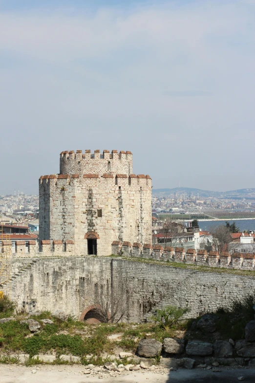 a castle sitting on top of a hill next to a body of water, istanbul, circular gate in a white wall, silo, towering over a city