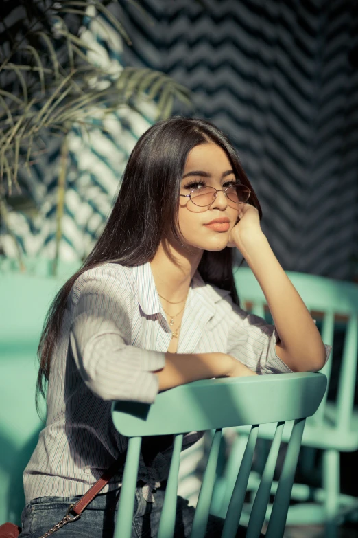 a beautiful young woman sitting on top of a green chair, inspired by Elsa Bleda, pexels contest winner, hurufiyya, with square glasses, madison beer, beautiful iranian woman, profile image