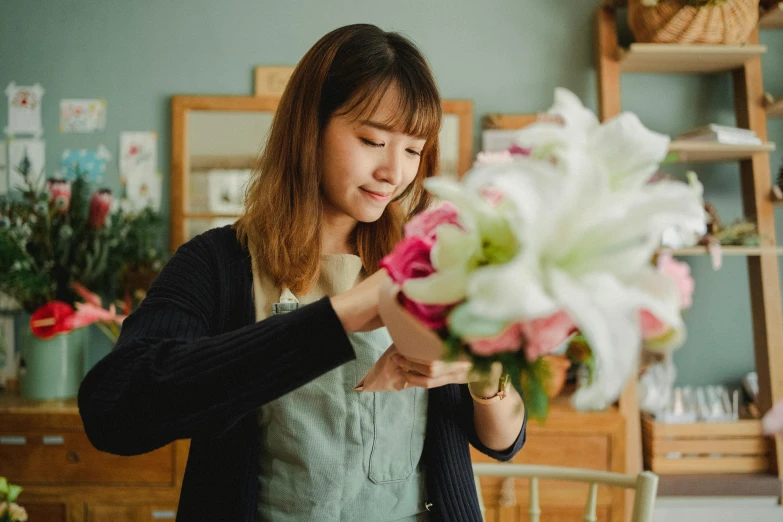 a woman is arranging flowers in a vase, inspired by Yukimasa Ida, pexels contest winner, beautiful young korean woman, professional work, alana fletcher, inspect in inventory image