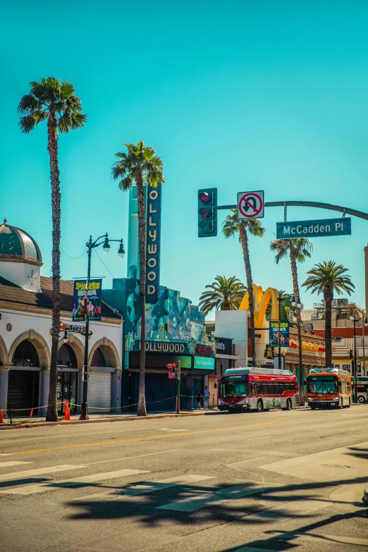 a street filled with lots of traffic next to tall palm trees, by Leo Michelson, trending on unsplash, art nouveau, hollywood promotional image, storefronts, square, on a sunny day