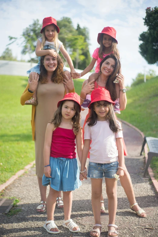 a family poses for a picture in a park, inspired by The Family Circus, pexels, incoherents, red hat, in sao paulo, beautiful girls, avatar image