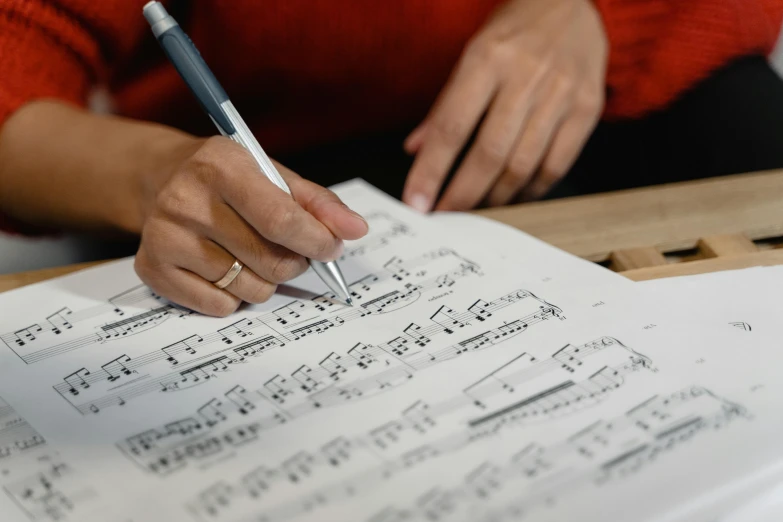 a woman is writing music notes on a piece of paper, pexels contest winner, analytical art, thumbnail, conductor, high quality photo, te pae