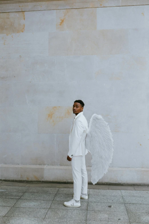 a man standing in front of a wall holding an umbrella, by Cosmo Alexander, pexels contest winner, baroque, large white wings, ashteroth, wearing white pajamas, winged victory