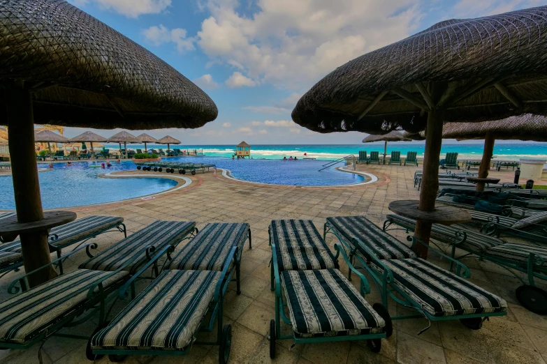 a group of lounge chairs sitting on top of a sandy beach, pools, avatar image, varadero beach, profile image