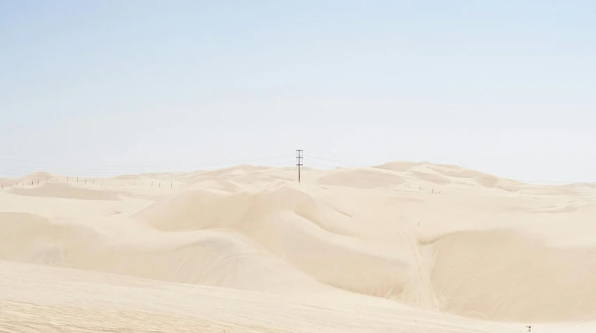 a man riding a snowboard down a snow covered slope, inspired by Zhang Kechun, unsplash contest winner, postminimalism, in the desert beside the gulf, power lines, buried in sand, album cover