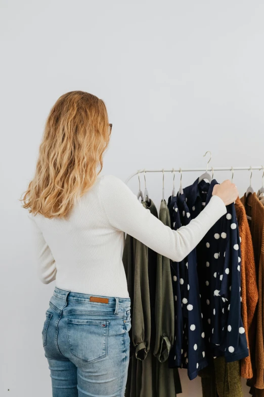 a woman standing in front of a rack of clothes, inspect in inventory image, centered design, plain background, britt marling style