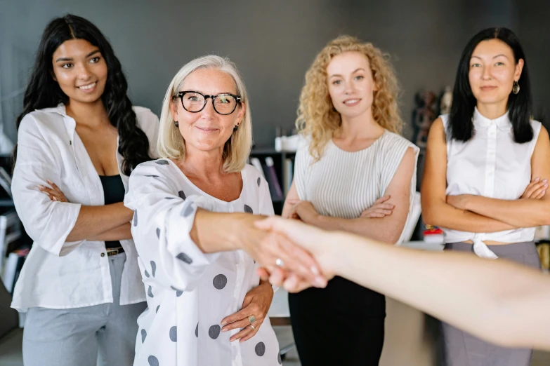 a group of women standing next to each other shaking hands, by Lee Loughridge, pexels contest winner, female in office dress, avatar image, lachlan bailey, looking to camera