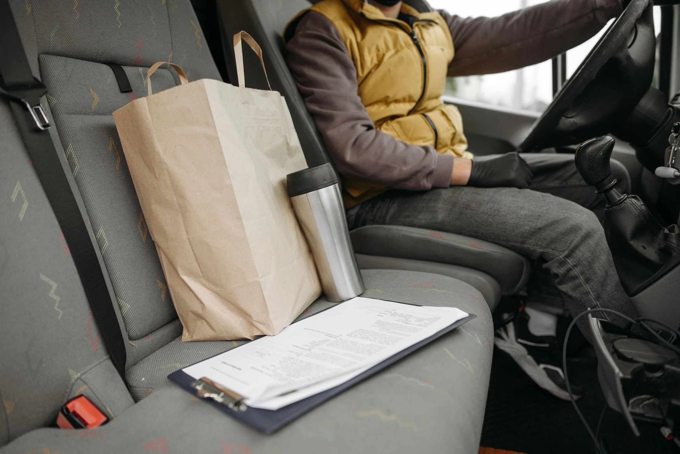 a man sitting in the driver's seat of a car, with notes, urine collection bag, yellow and charcoal leather, avatar image