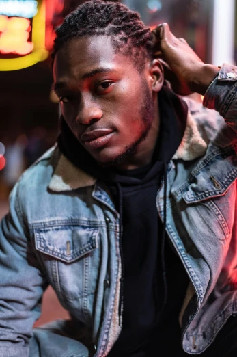 a man sitting on the ground in front of a neon sign, an album cover, trending on pexels, realism, man is with black skin, headshot profile picture, model wears a puffer jacket, blurry