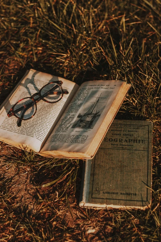 an open book sitting on the ground next to a pair of glasses, a picture, unsplash contest winner, in a grass field, an old, magazine photography, 15081959 21121991 01012000 4k