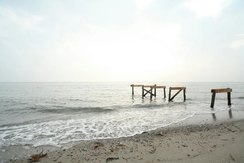 a couple of benches sitting on top of a sandy beach, an album cover, by Karel Dujardin, unsplash, minimalism, venice biennale, hazy water, chiba prefecture, an abandoned