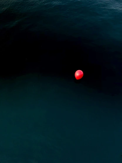 a red ball floating on top of a body of water, in a dark, mariana trench, pennywise, balloon