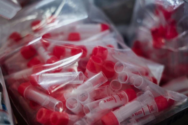 a close up of a bunch of red and white pills, by Daniel Lieske, pexels, pathology sample test tubes, in plastic, white t-shirt with red sleeves, tubes and gauges