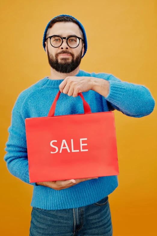 a man in a blue sweater holding a red sale bag, pexels contest winner, magic realism, square rimmed glasses, bearded, home shopping network, multicoloured